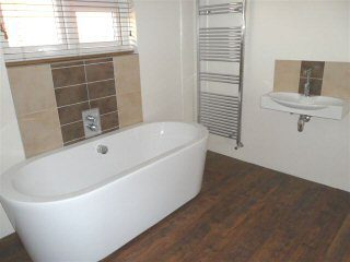 Modern bathroom with freestanding bath and wood-effect floor